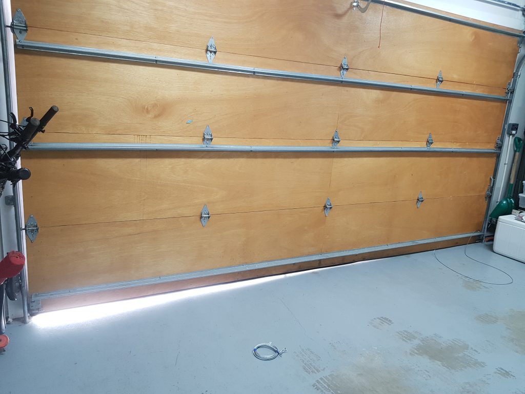 View of Garage Door that has cables that are off on the right side resulting in the Left Side to showing light.