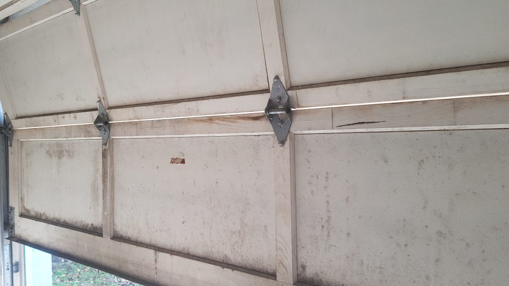 Inside View of Damaged Panel on Wooden Garage Door in Surrey