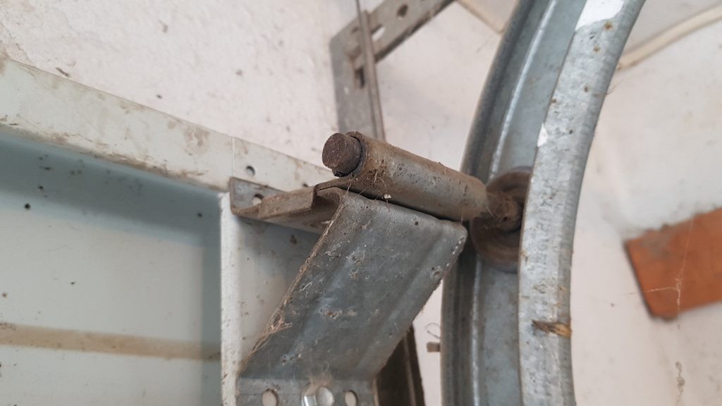 A old garage door roller that is in need of lubrication.