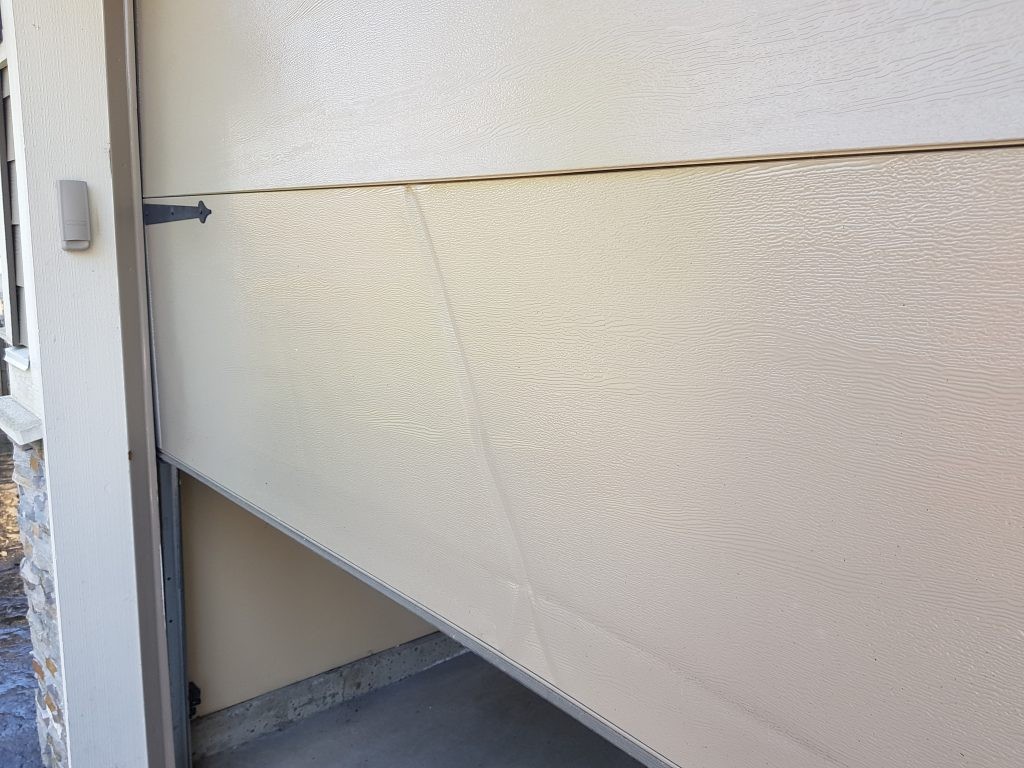 View of garage door that has been hit from a vehicle