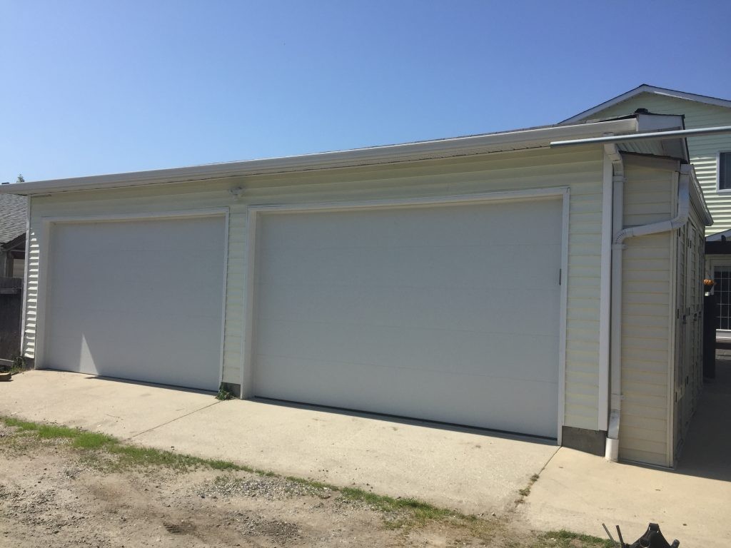 View of flush garage doors that have been installed as a replacement for wood doors. These garage doors are flush and white with no windows.