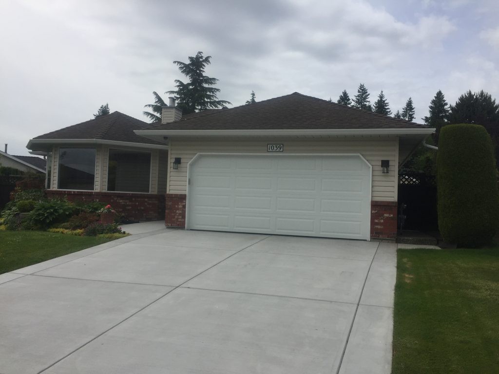 View of finished garage door install with long panels in a factory white painted finish.