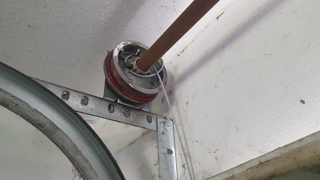 View of a garage door drum that has the cables not properly attached / secured. 